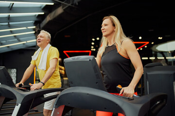 Active older couple staying fit with gym workouts. Mature man and woman working out on training...