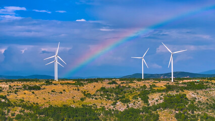 AERIAL: A striking rainbow arcs over wind turbines set against rugged landscape.