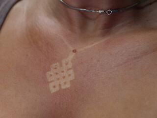 CLOSE UP, DOF: White mark of necklace pendant on reddened skin of unknown woman. Young lady was...