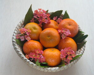 Mandarin fruit with leaves, kalanchoe flowers, on woven basket,othe mandarin orange, Citrus...