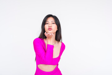 Young woman in vibrant magenta dress blowing a kiss isolated on white background