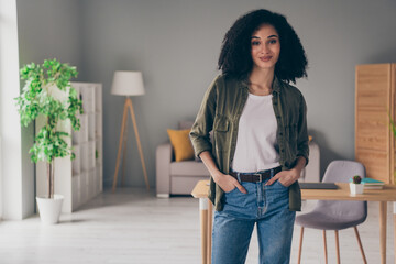 Photo of pretty young woman put hands pockets posing wear khaki shirt modern interior house indoors