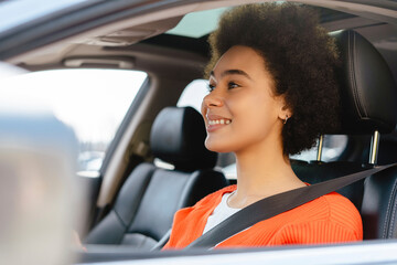 Smiling woman driving car. Cheerful young happy African American female driving car with safety