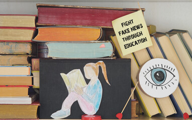 Fight against fake news concept,sign with slogan fight fake news drawing of a reding girl and books.Education,learning,fight stupidity through education concept