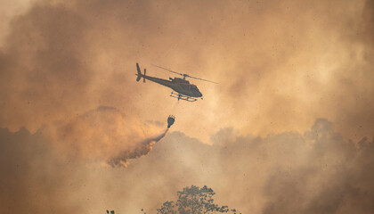 Fire fighting helicopter carry water bucket to extinguish the forest fire.