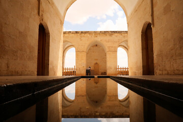 Water in a pond, pool reflecting the arches, vaults and doors of the Sultan Isa Medrese, Madrasa,...