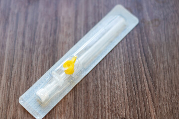 A white needle with a yellow tip rests on a hardwood table in the kitchen