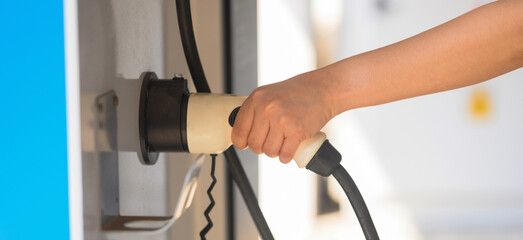Hand is holding fast electric car charger green energy environment friendly driving vehicle...
