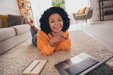 Photo portrait of lovely young lady lying floor netbook studying dressed casual orange clothes cozy day light home interior living room