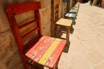 Fototapeta na wymiar A row of colorful wooden chairs in a row in front of a wall in the old town of Mardin, Turkey
