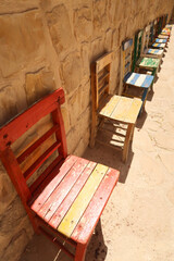 Colorful wooden chairs placed in a row in front of a wall in the old town of Mardin, Turkey