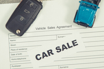 Blue toy car, key and vehicle sales agreement. Inscription car sale. Sales and buying new or used...