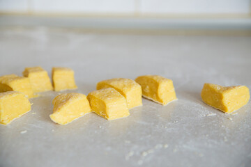 Close up of raw dough cut in cubes, homemade noodles preparation in a kitchen counter table. 