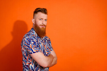 Side profile photo of confident serious brutal man wear print shirt holding arms crossed isolated on vibrant orange color background