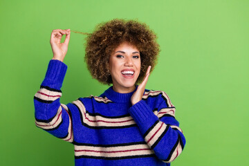 Portrait of toothy beaming pleasant girl with perming coiffure dressed knit pullover holding curl...