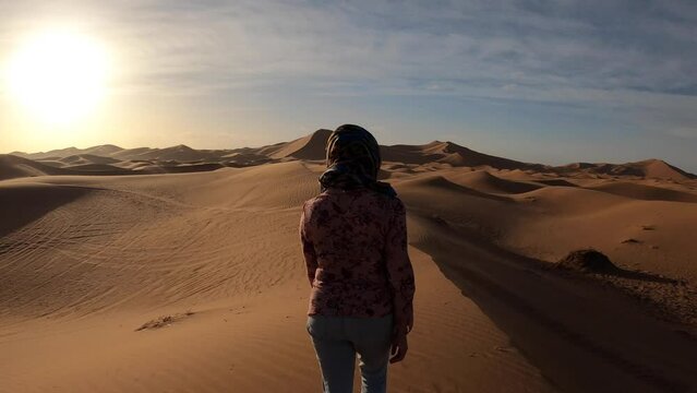 Woman in the dunes at sunrise, Erg Chebbi, Sahara Desert, Morocco