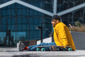 A Young Man In A Vibrant Yellow Jacket And Baseball Cap Enjoys A Sunny Day Skateboarding In An...