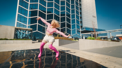 A Vibrant Young Woman Dances Energetically In A Modern Urban Setting, Her Pink Boots And Dynamic Pose Reflecting A Lively Spirit Against A Background Of Towering Glass Buildings Under A Clear Blue Sky