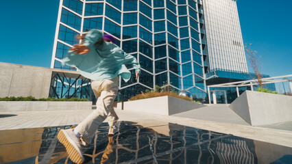 Dynamic Image Of A Young Person Energetically Breakdancing In A Modern Urban Plaza, Reflecting Youth Culture And The Vibrancy Of Street Dance Against A Background Of Towering Glass Buildings.