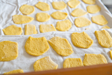 Top view above overhead of pieces of homemade noodle dough in kitchen with natural backlight, home atmosphere.