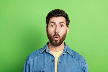 Photo of impressed positive guy dressed jeans shirt empty space isolated green color background