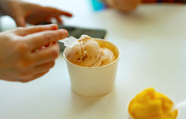 hand scoop ice cream in paper cup, woman hand with spoon. Soft view