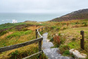 Fototapeta na wymiar Narrow fenced path with steps leading to a clifftop viewpoint on a lighthouse along the coast of north Wales on a foggy summer day