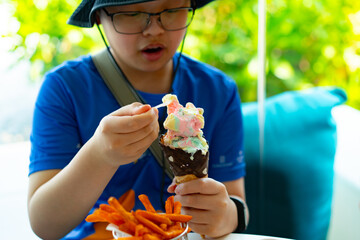 boy with hat eat ice cream cone by spoon