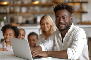Young Black parent dad working from home office, African American father holding baby child daughter using laptop computer spending time with diverse multiracial family at home in the kitchen