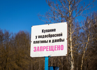Warning sign that state in Russian, not allowed swimming by the dam and spillway dam. Danger