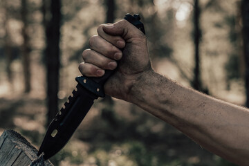 Hand man with hunting knife for survival in the forest. Concept recreation and survival in forest.