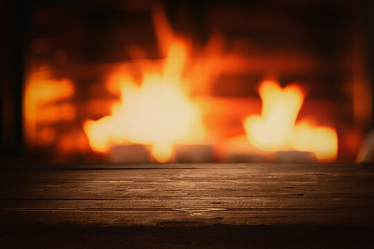 empty dark brown wooden tabletop for product display on blurred wood burning fireplace background