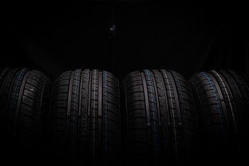 Row of car tires on black background.
