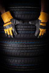 Close up of car tires and hand with gloves on black background. Concept of car service.