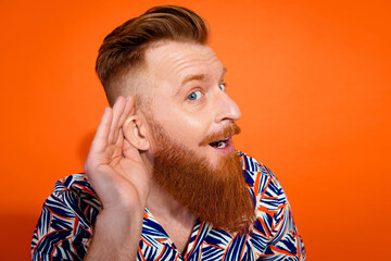 Photo of funky excited guy dressed print shirt hand ear listening gossips isolated orange color background