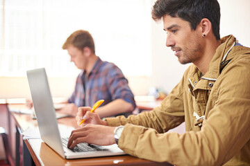 College student, man and laptop with typing in classroom for studying, research or assessment for development. Person, education and learning on computer to search for academic article at university
