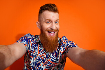 Photo of cheerful good mood guy dressed print shirt recording video vlog smiling isolated orange color background