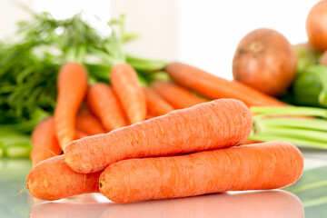 Peeled sweet carrots on the table with vegetables.