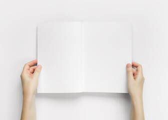 Hands holding an open magazine with empty white pages top view