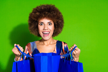 Photo of positive glad woman wear trendy print clothes hand hold package isolated on vibrant green...