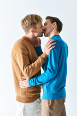 Two men in casual attire kiss passionately.