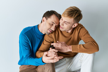 Two men in casual attire sitting together, absorbed in a cell phone.