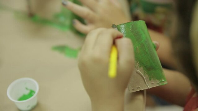 close-up of a child painting a toy made with recyclable material. Cardboard toilet paper