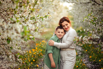mother and teenage son on a walk in a blooming spring garden. family leisure and recreation