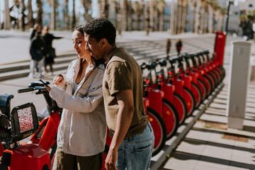 Intimate moment shared between a couple selecting public bicycles in sunny Barcelona