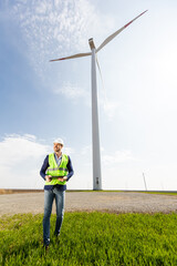 Engineer Inspecting Wind Turbine Efficiency in Vast Green Field on a Sunny Day.