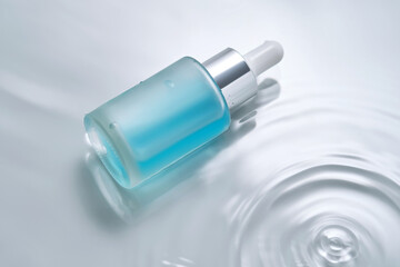 Bottles of cosmetics with a dropper in water on a blue background.