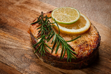 salmon steak, fried, on a cutting board, top view, rosemary, lemon and lime, homemade, one serving, no people,
