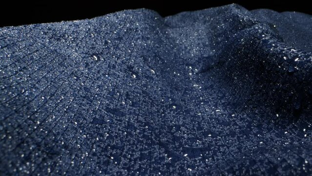 Waterproof clothing for tourism. Blue cloth texture with water drop close-up macro. Repellent waterproof breathable fabrics. Innovation waterproofing material test