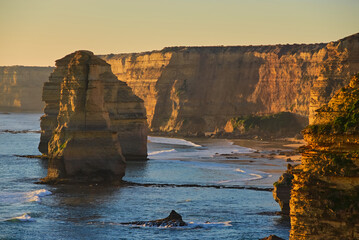 Beautiful view of the southern coast of Victoria, Australia as the setting sun casts a golden hue over limestone cliffs and rock formations.